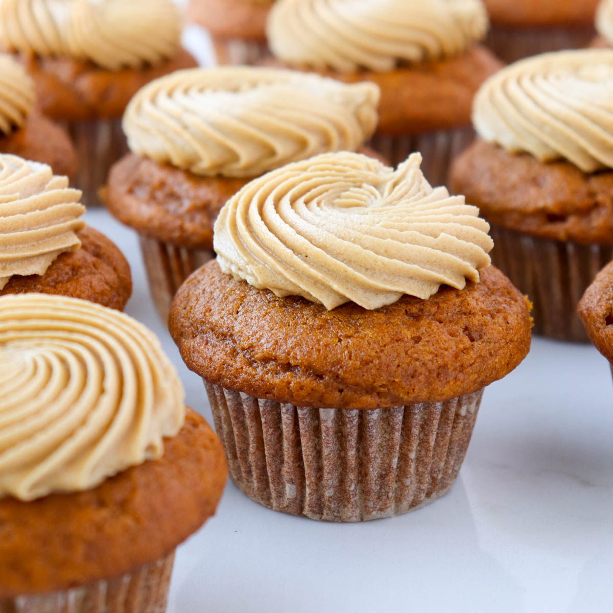 Pumpkin cupcakes topped with a swirl of frosting.