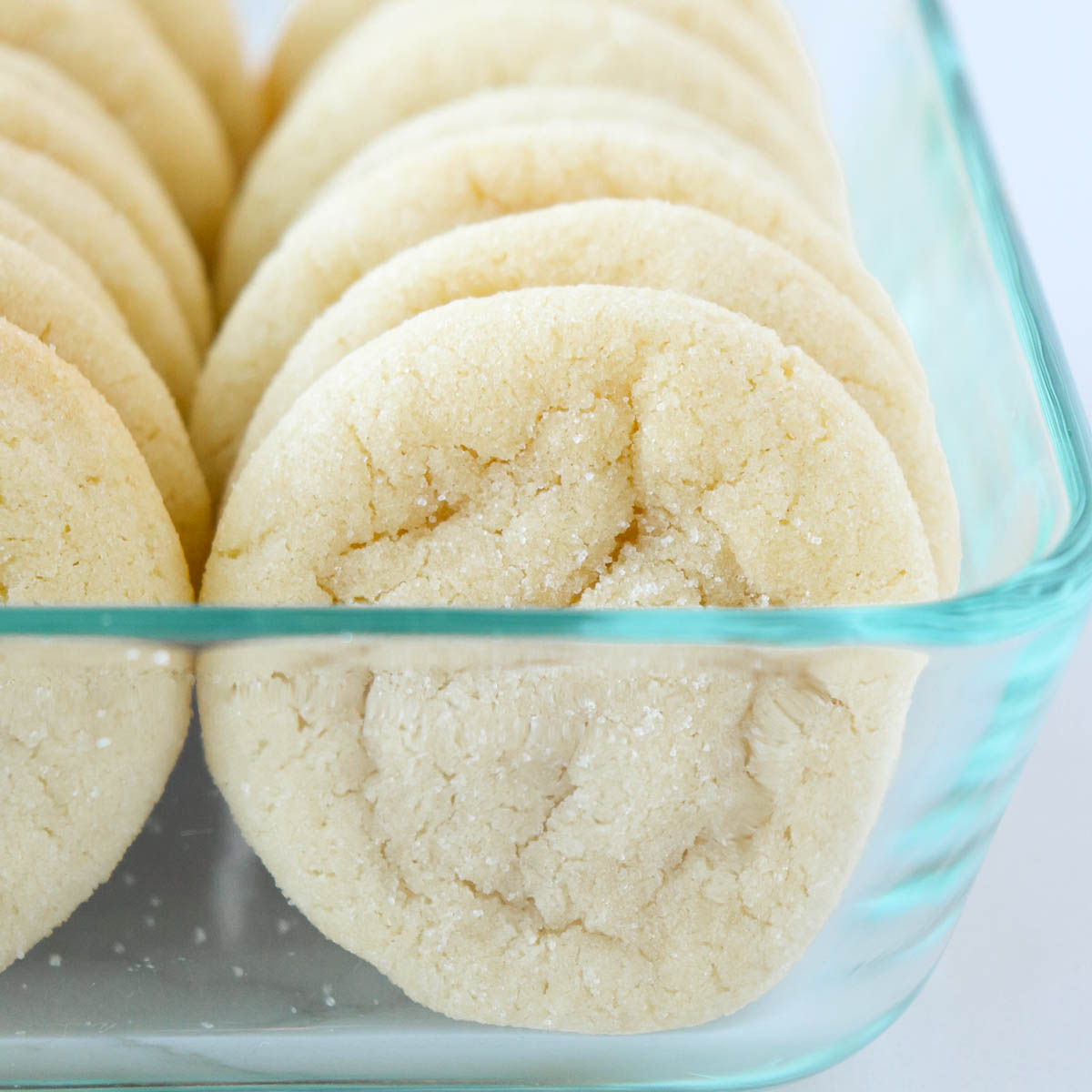 Sugar cookies in a glass storage container.