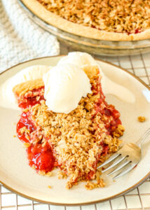 slice of strawberry rhubarb pie topped with scoop of vanilla ice cream