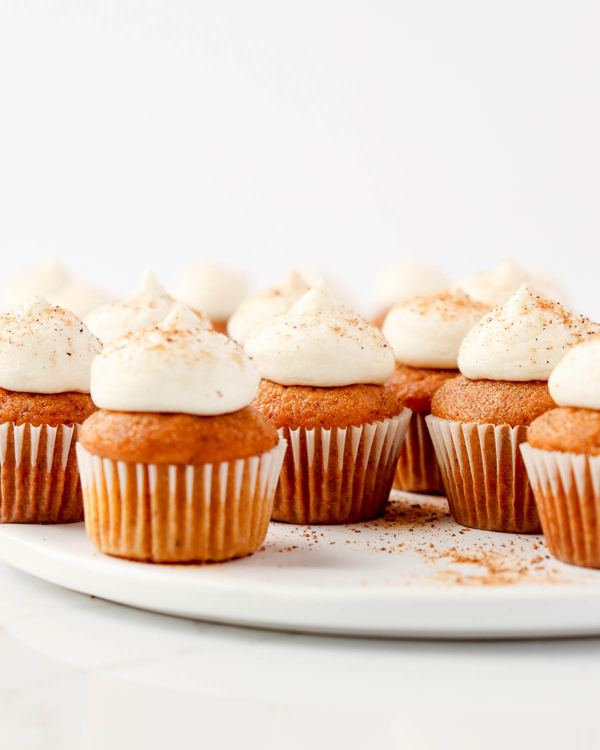 Mini pumpkin cupcakes on a white plate.