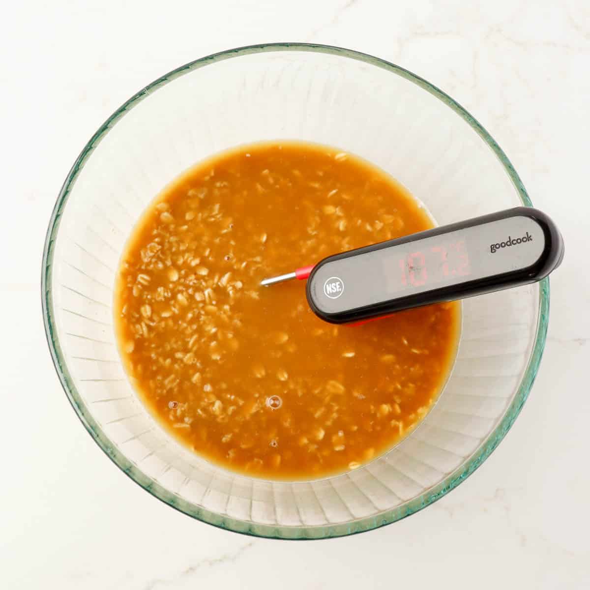 Oats, boiling water, molasses, brown sugar, and salt combined in a mixing bowl with a temperature probe.