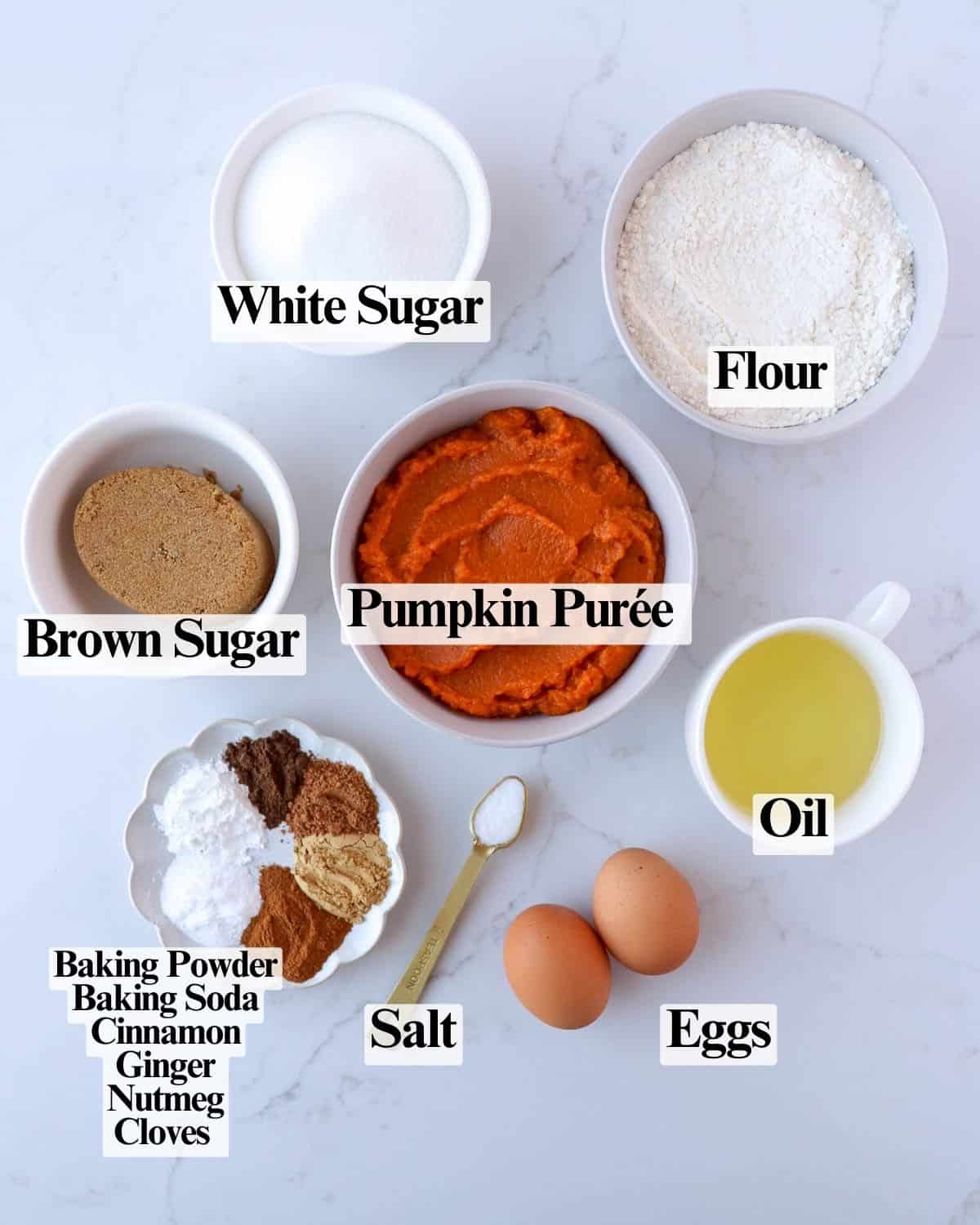 Ingredients for pumpkin cupcakes: white sugar, brown sugar, oil, eggs, pumpkin purée, flour, baking powder, baking soda, salt, cinnamon, ginger, nutmeg, and cloves.