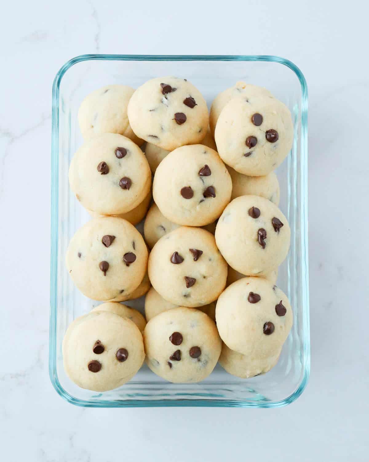 Shortbread cookies with chocolate chips in a glass storage container.