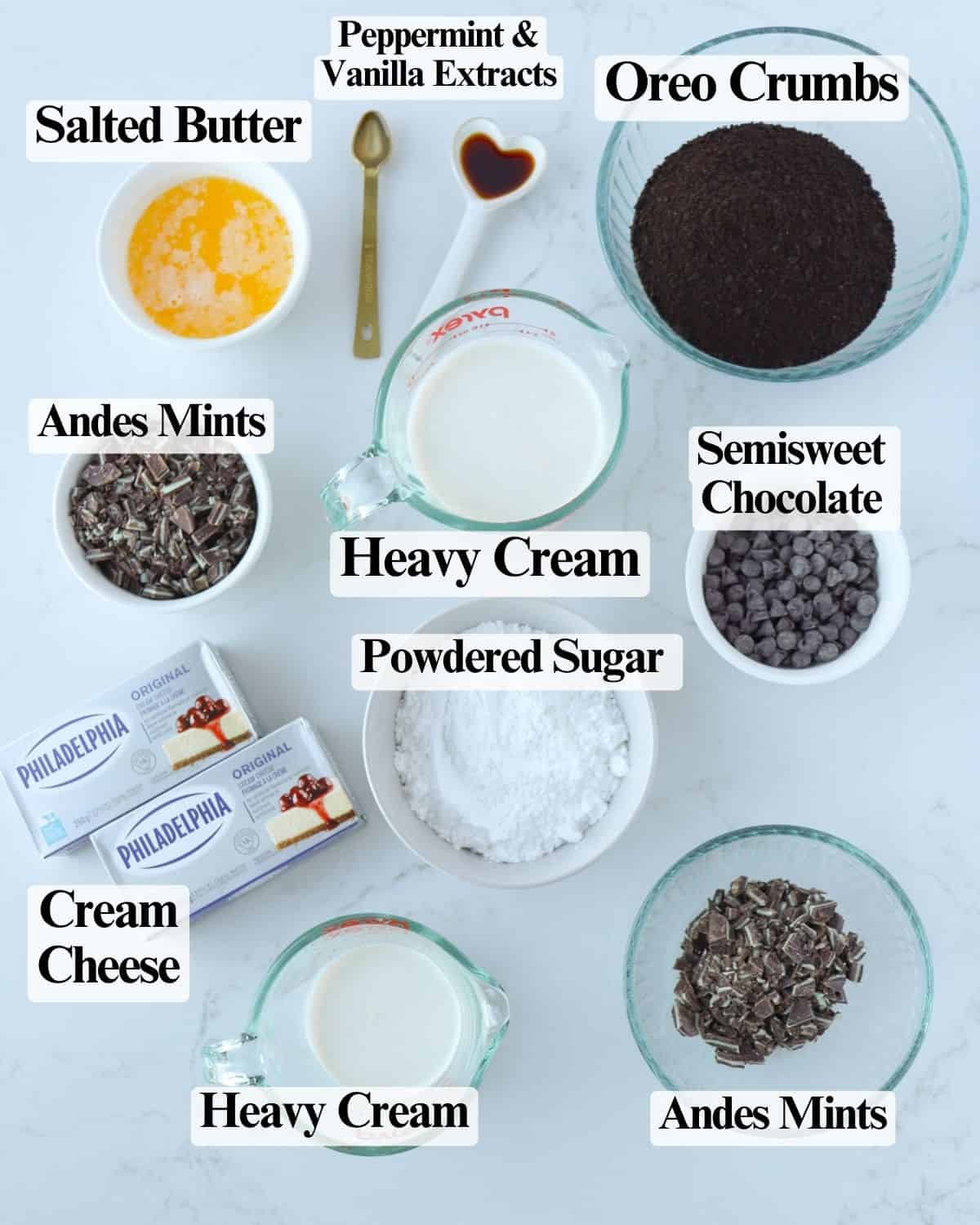 Ingredients for chocolate mint cheesecake: melted butter, Oreo crumbs, cream cheese, heavy cream, semisweet chocolate chips, chopped Andes mints, peppermint extract, vanilla, and powdered sugar.