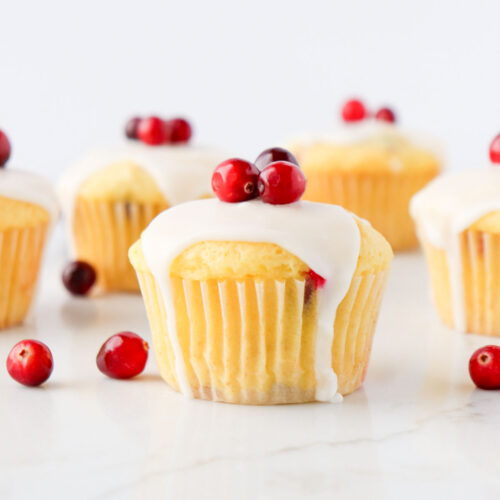 Lemon cranberry muffin topped with white icing and fresh cranberries on top.