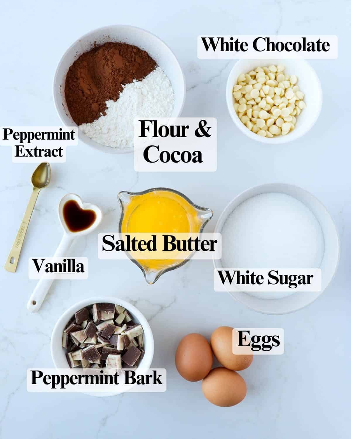 Ingredients for peppermint brownies: melted butter, white sugar, eggs, vanilla, peppermint extract, flour, cocoa, white chocolate chips, and chopped peppermint bark.