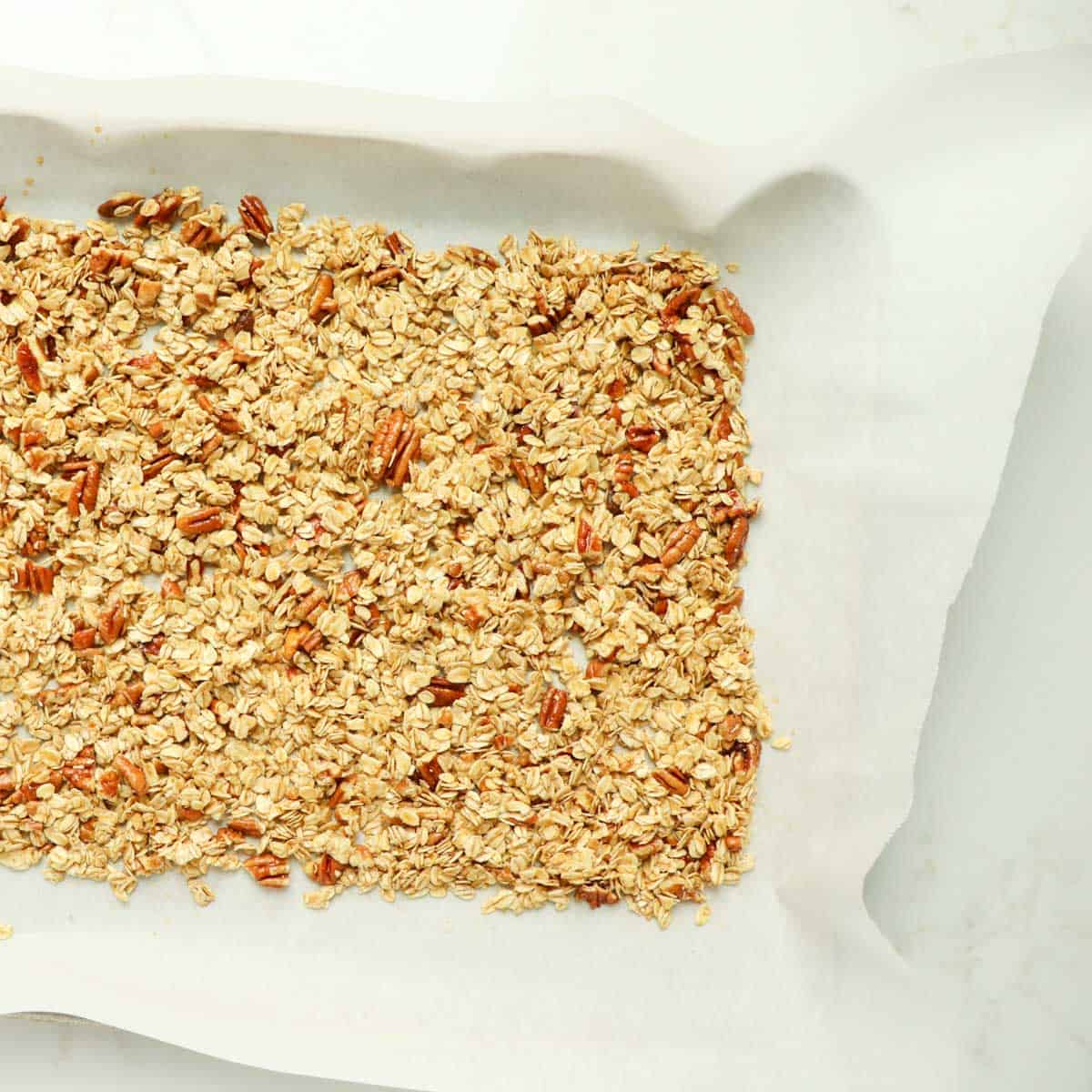 Unbaked granola on a baking pan lined with parchment paper.