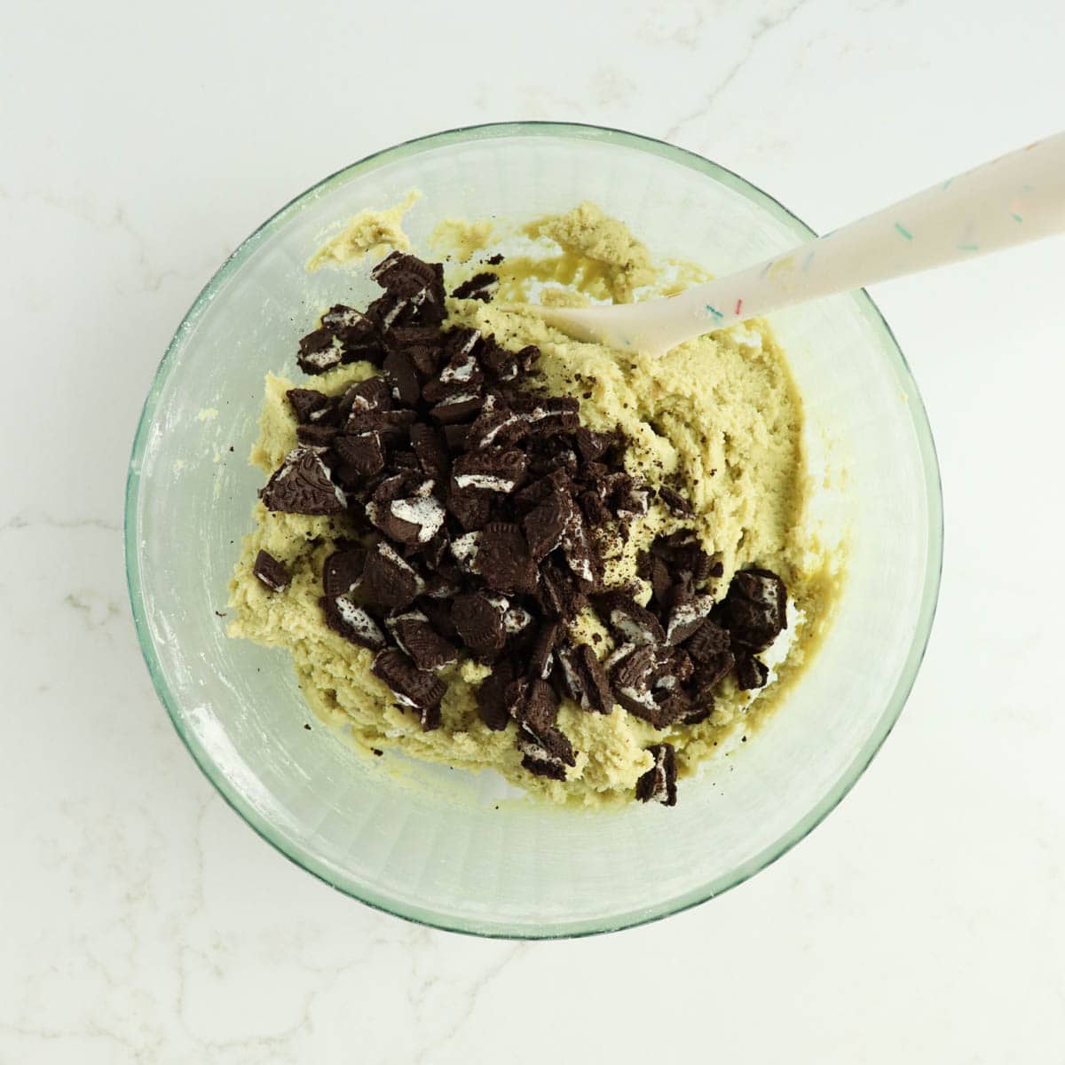 Chopped Oreo cookies added to bowl of cookie dough.