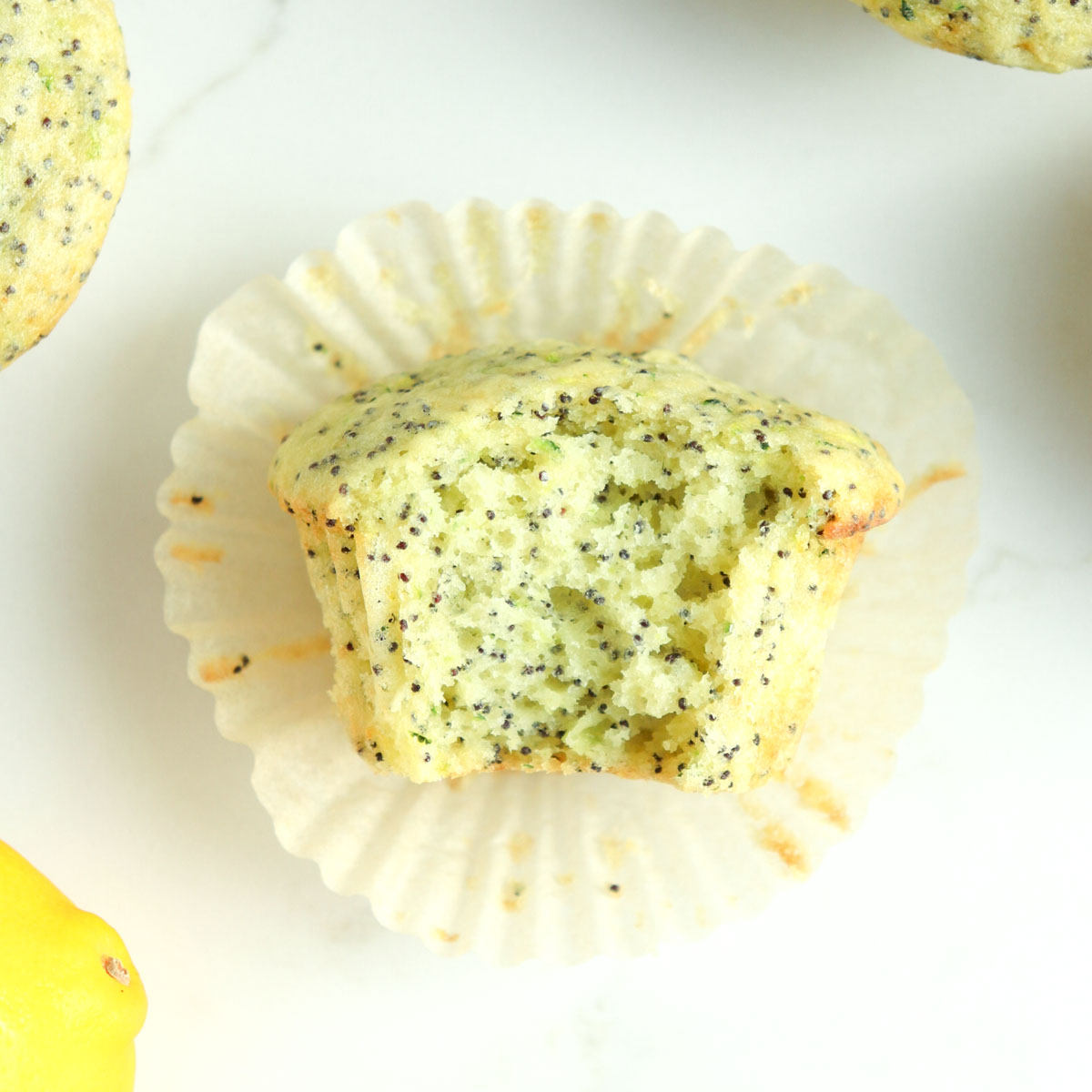 Zucchini lemon poppy seed muffin with a bite taken out of it.