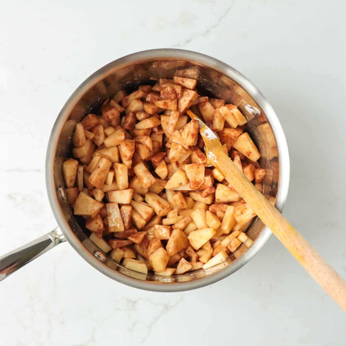Chopped apples and other filling ingredients in a metal pot before cooking.