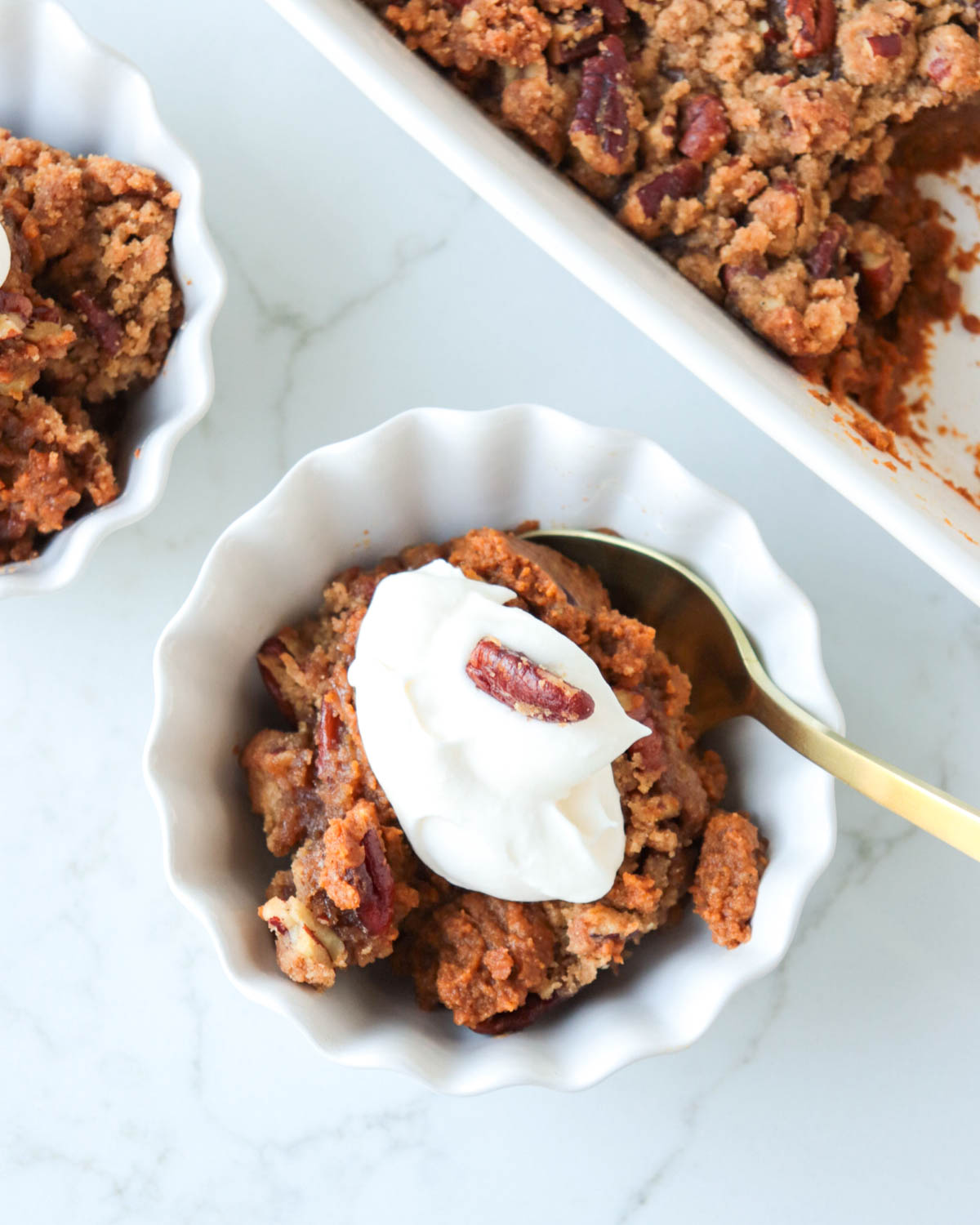 Pumpkin crisp topped with whipped cream in a white dessert bowl.