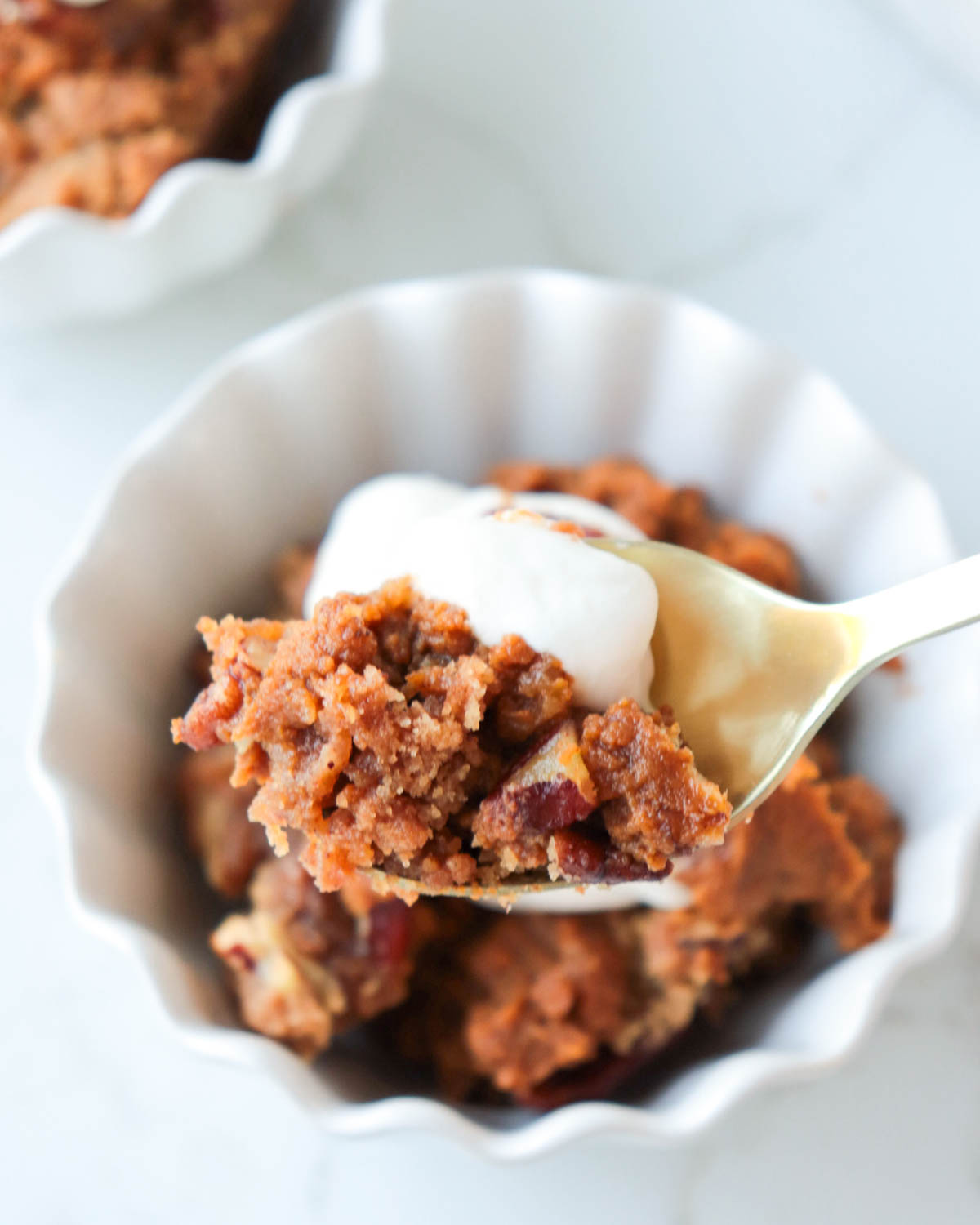 Spoonful of pumpkin crisp with whipped cream on top.