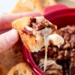 Baked brie topped with pecans on a slice of baguette.