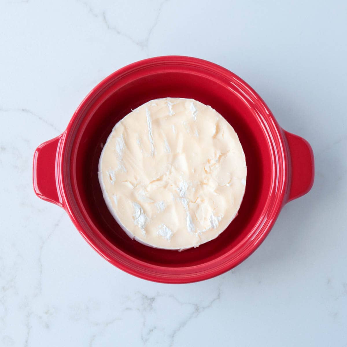 Brie in a red brie baking dish.