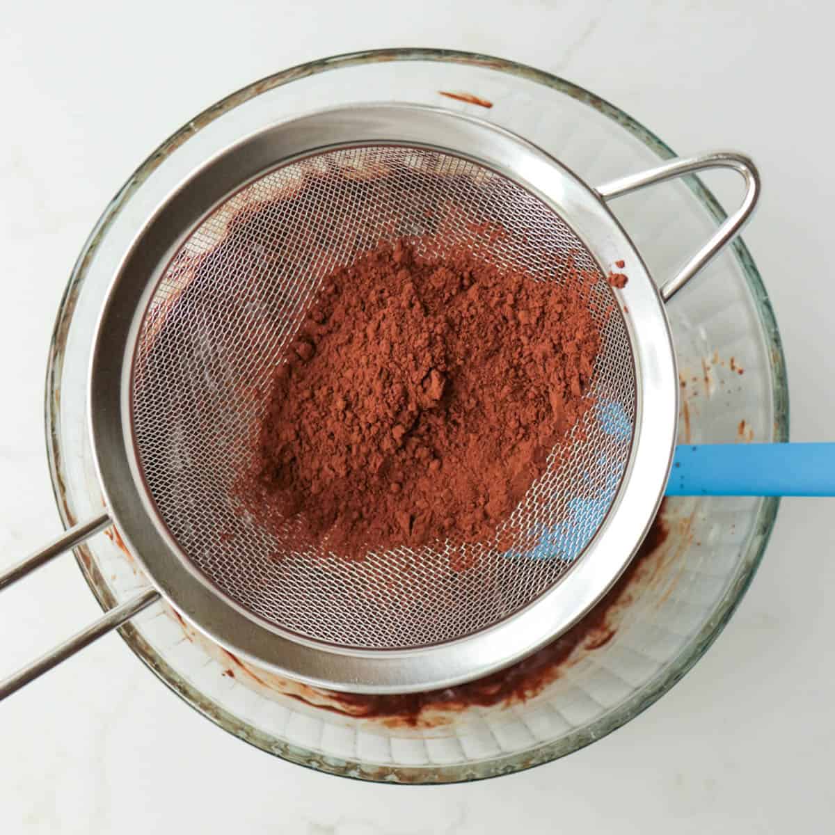 Sifting cocoa powder into the bowl.