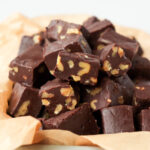 Pieces of chocolate walnut fudge in a paper-lined dish.