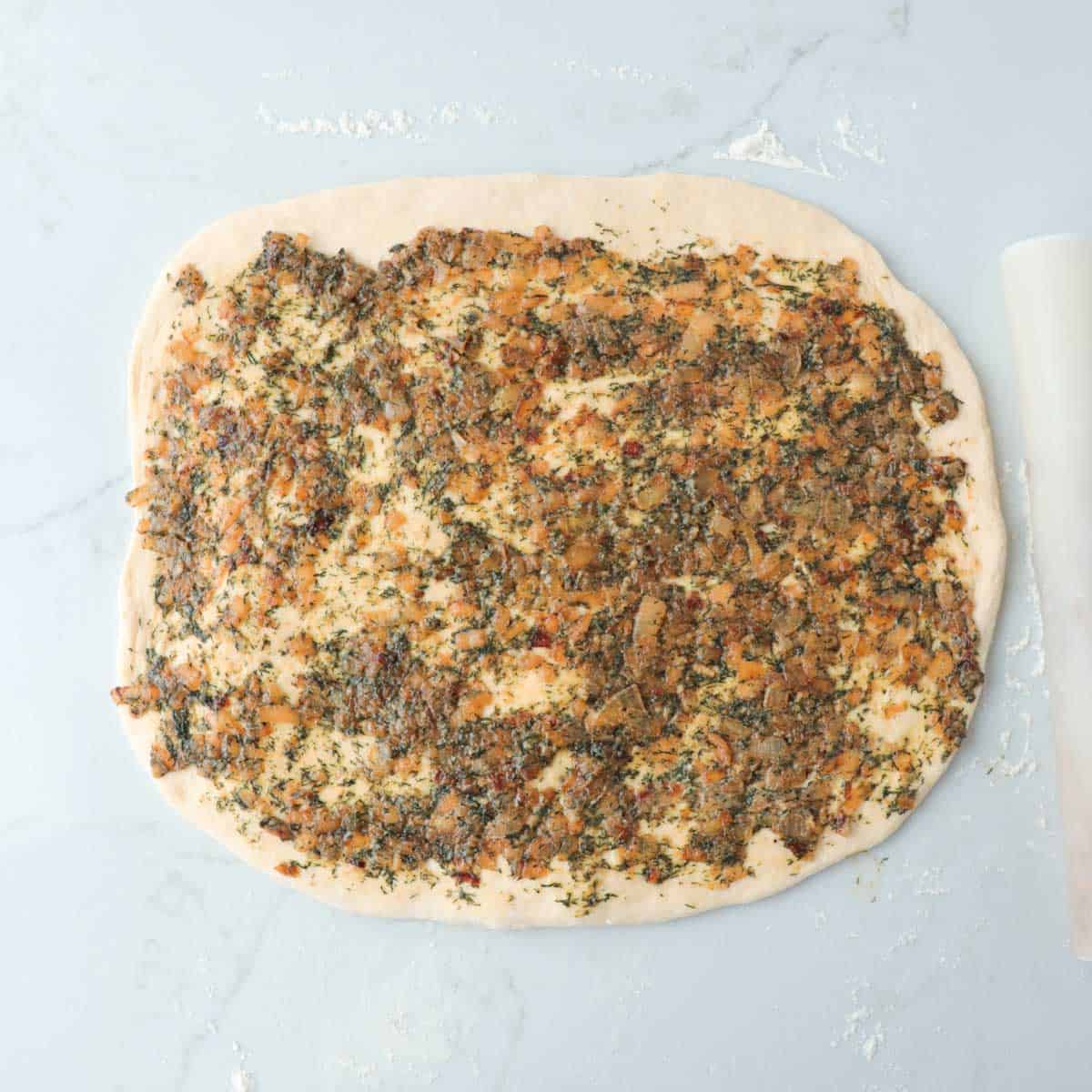Onion and dill mixture spread onto rolled out dough.