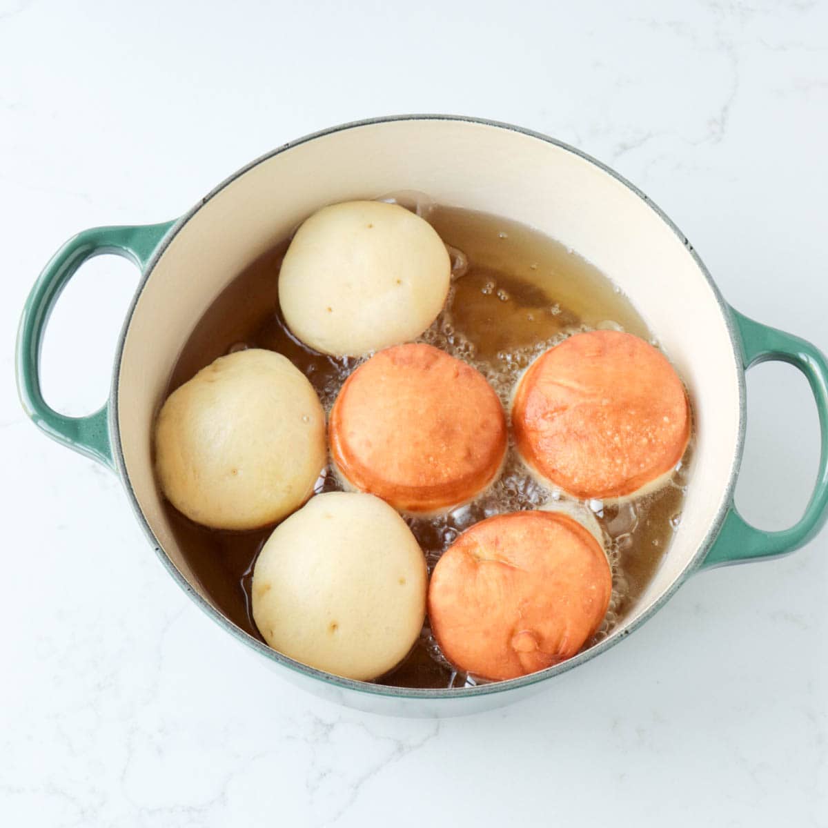 Doughnuts frying in hot oil in a Dutch oven.