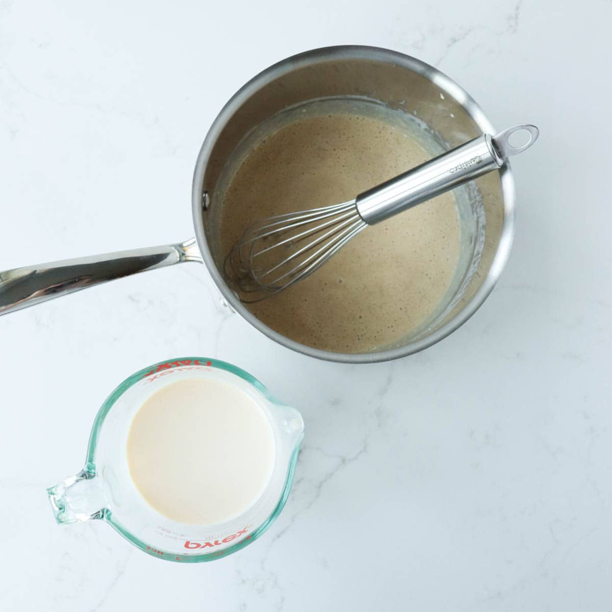 Eggnog whisked with flour and brown sugar in metal saucepan.