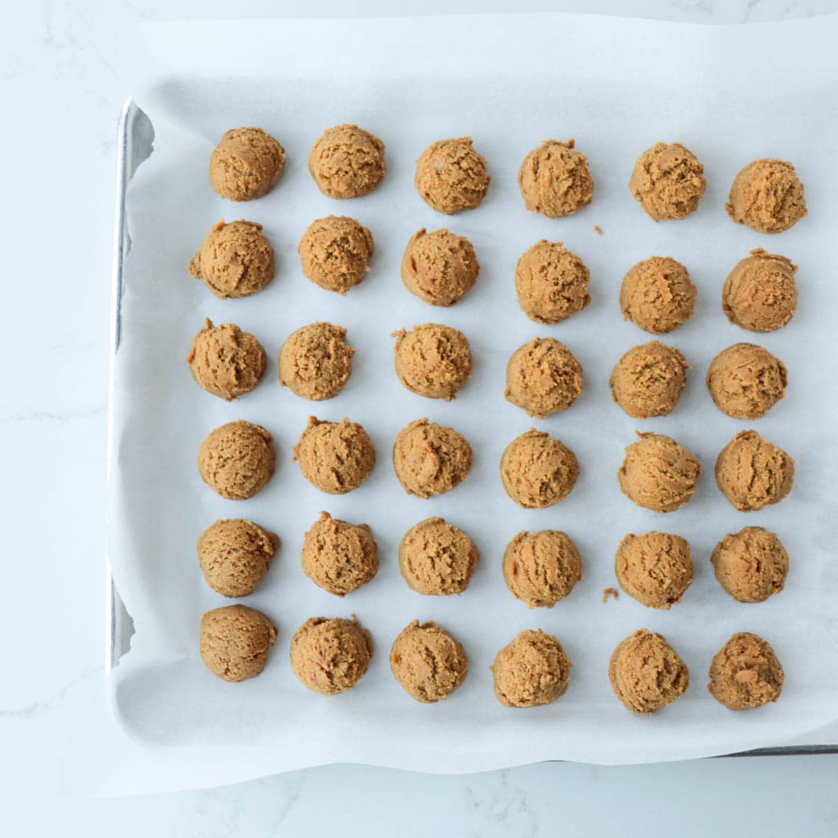 Cookie dough scooped onto parchment paper lined pan.