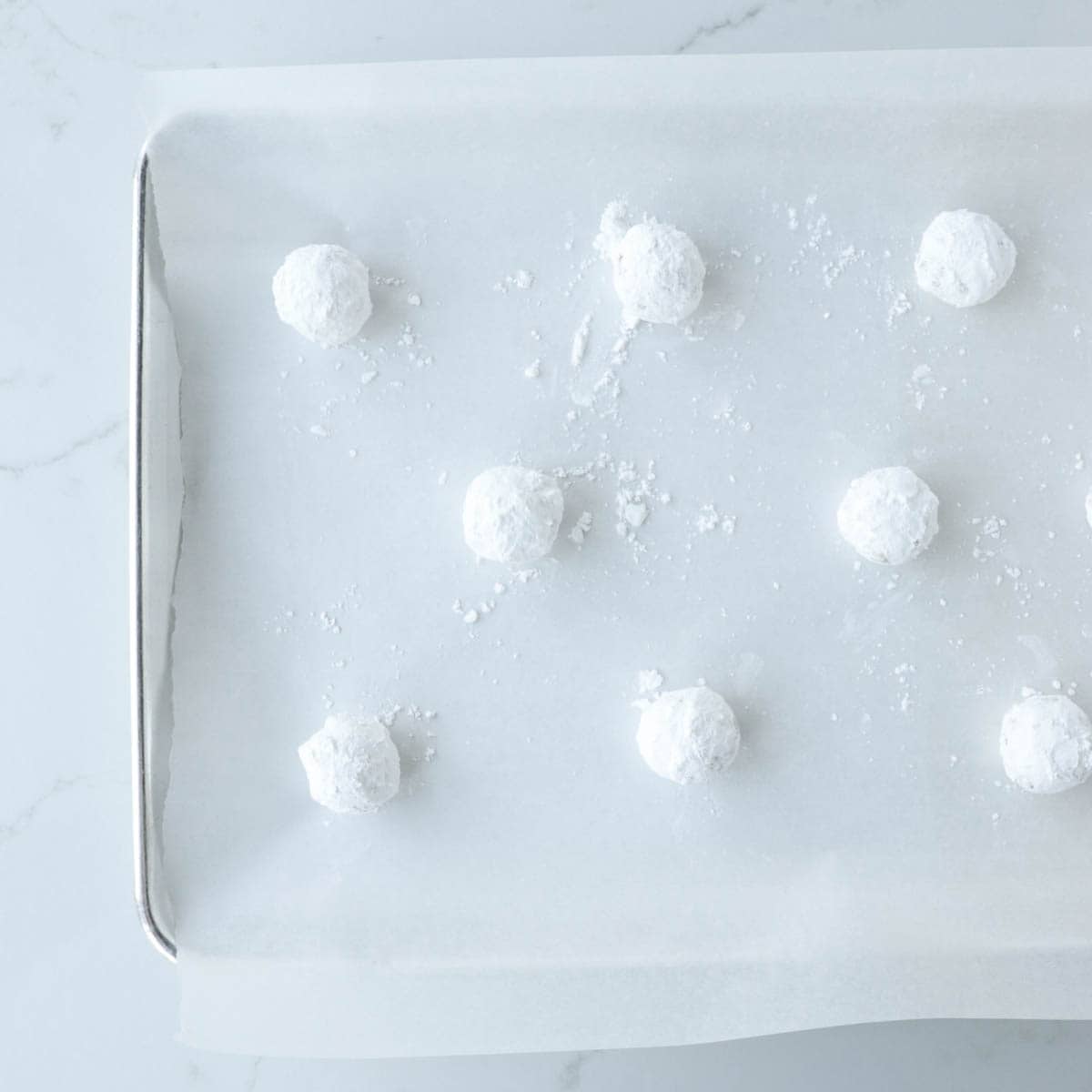 Sugar coated cookie dough balls on a baking pan.