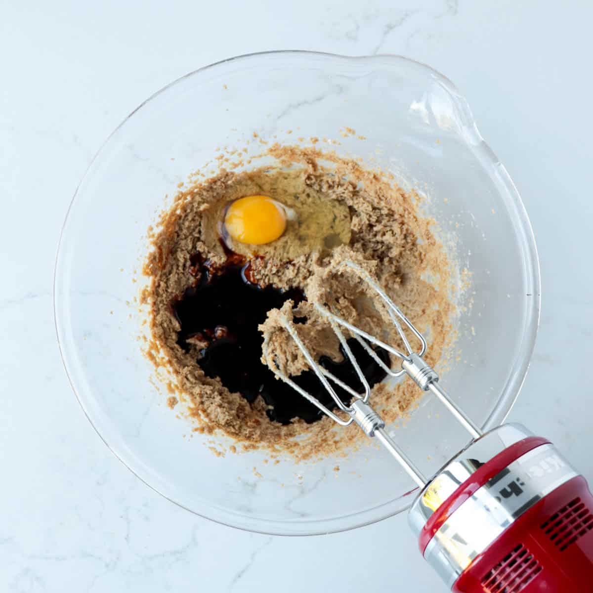 Egg and molasses added to creamed butter and brown sugar.