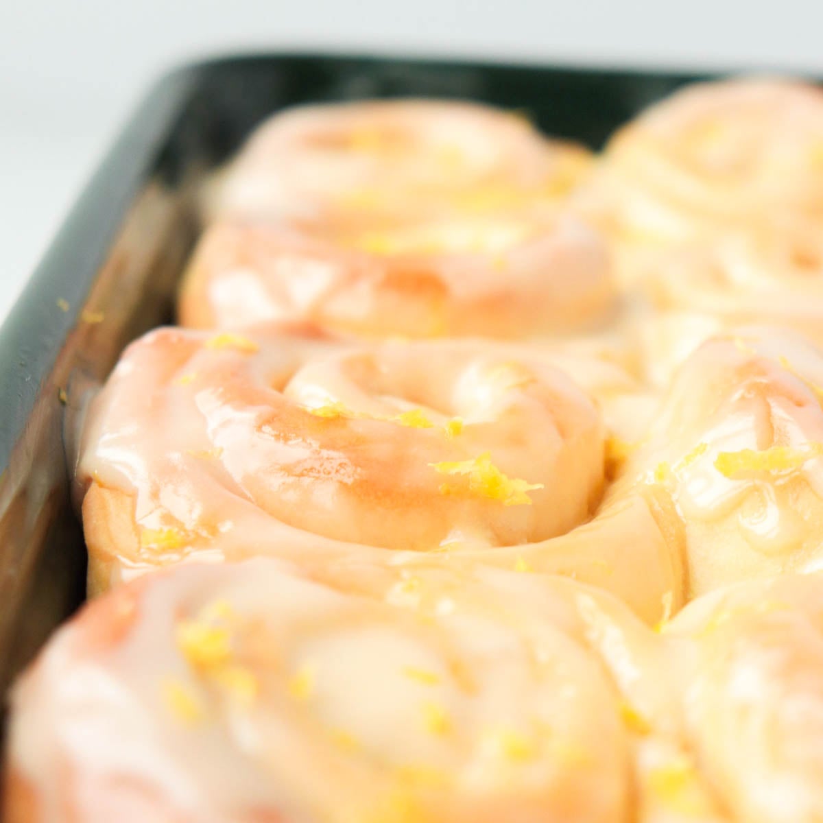 Lemon rolls in a dark green baking pan.