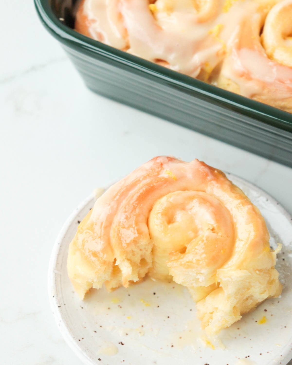 Lemon roll on a plate with a bite taken out of it.