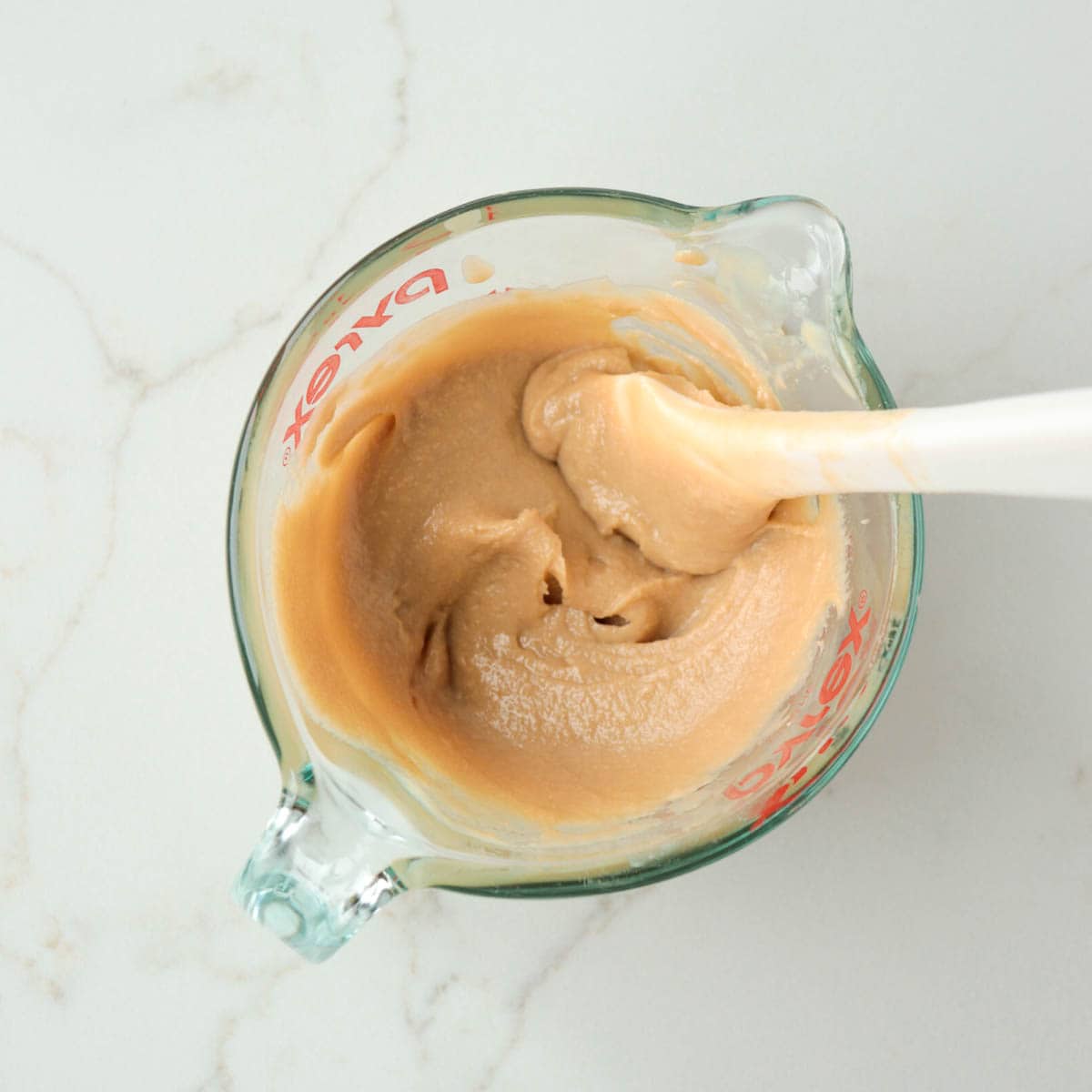 Tahini mixture combined in a glass measuring cup.