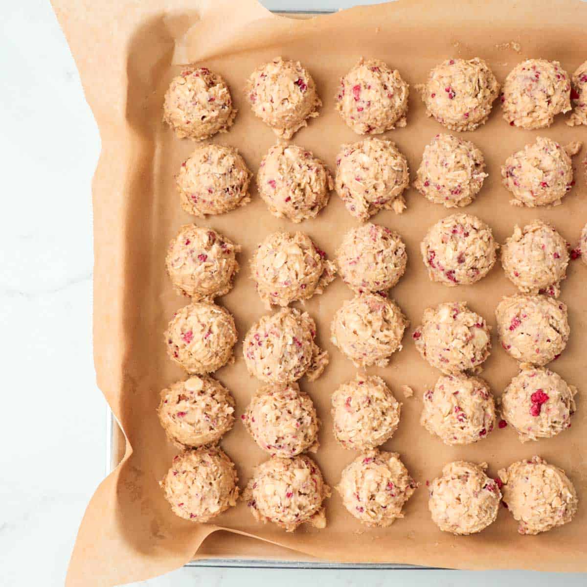 Cookie dough scooped onto a pan lined with parchment paper.
