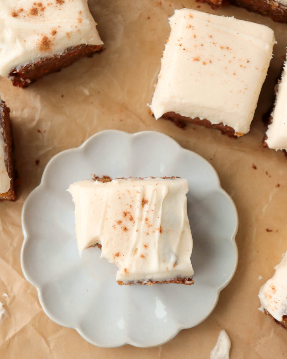Piece of carrot cake on a plate with a forkful taken out of it.