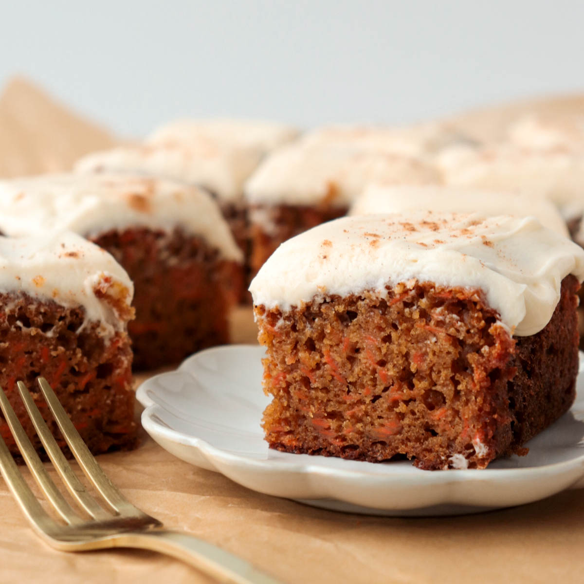 Piece of carrot cake topped with frosting on a white plate.