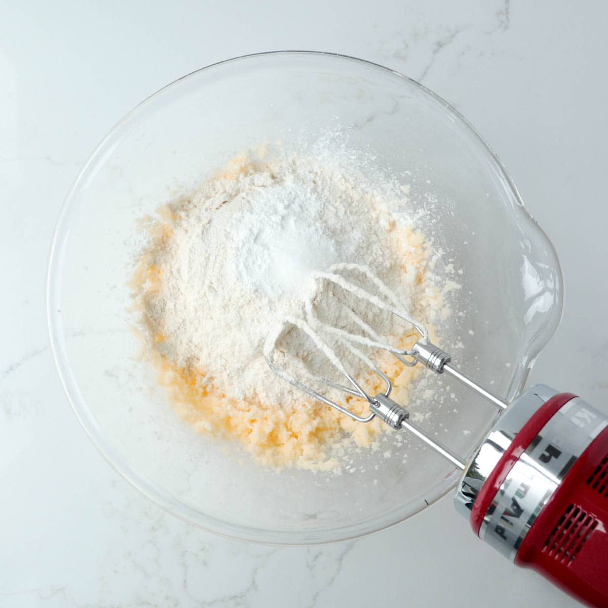 Dry ingredients added to butter in a glass mixing bowl.