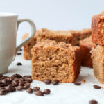 Piece of coffee cake next to a cup of coffee.