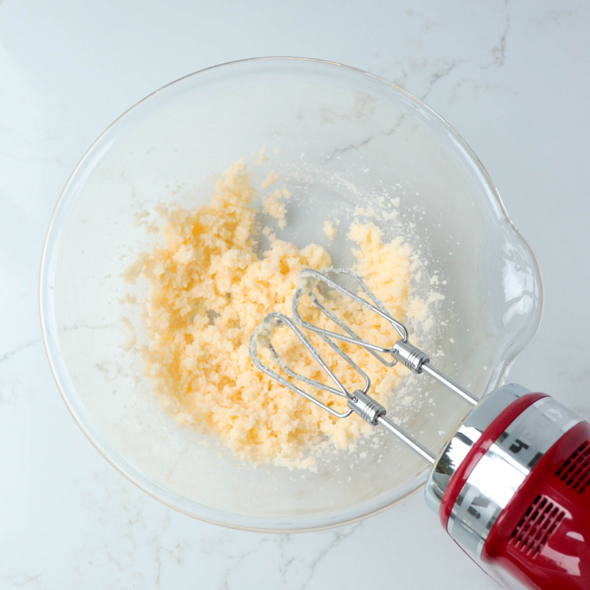 Butter and sugar creamed together in a glass mixing bowl.