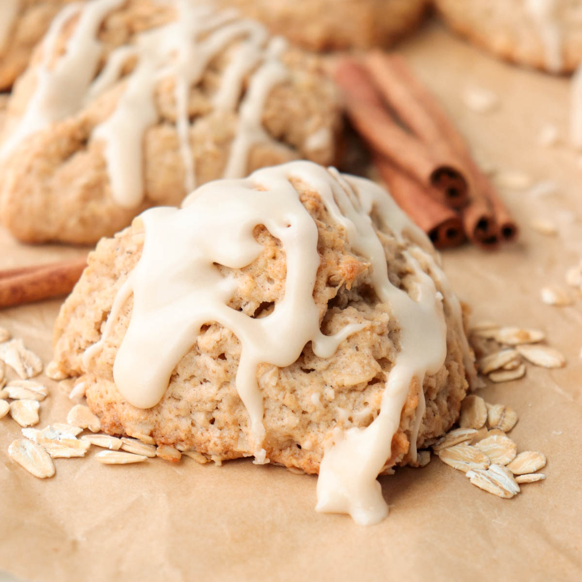 Scone topped with icing on a piece of parchment paper.
