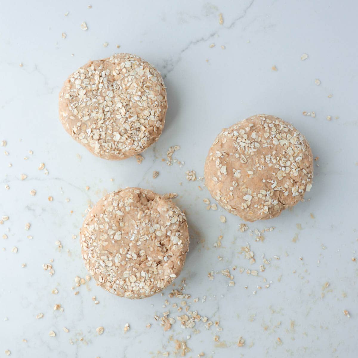 Three rounds of scone dough coated with oats.