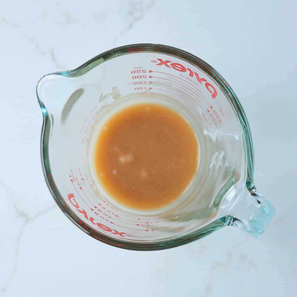 Brown sugar and whipping cream mixed together in a glass measuring cup.