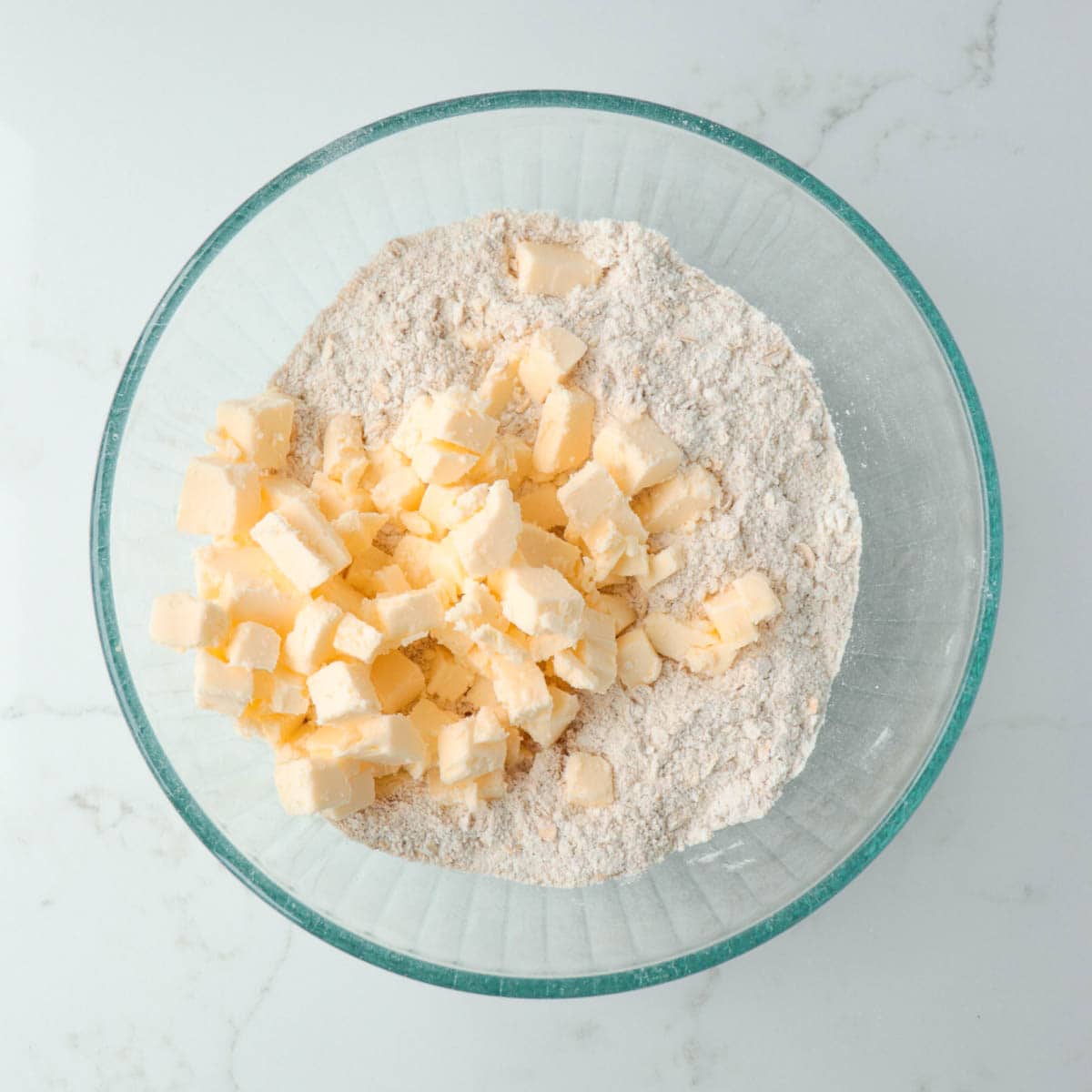 Cubes of butter added to bowl of combined dry ingredients.