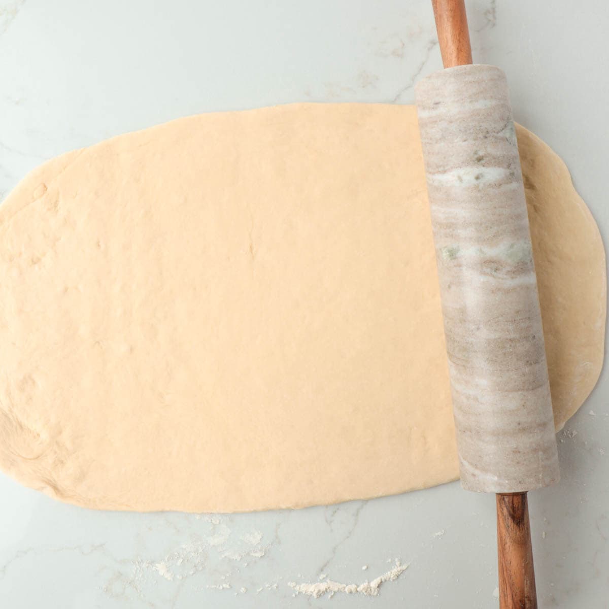 Rolling the dough out into a large rectangle.