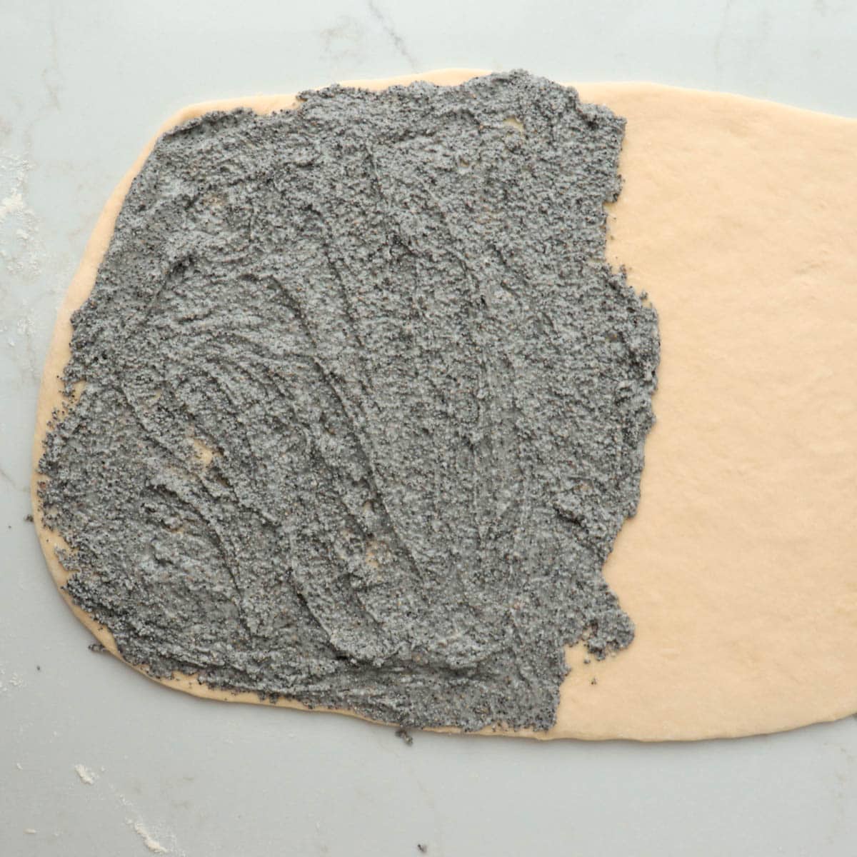 Poppy seed filling spread onto half of the dough.