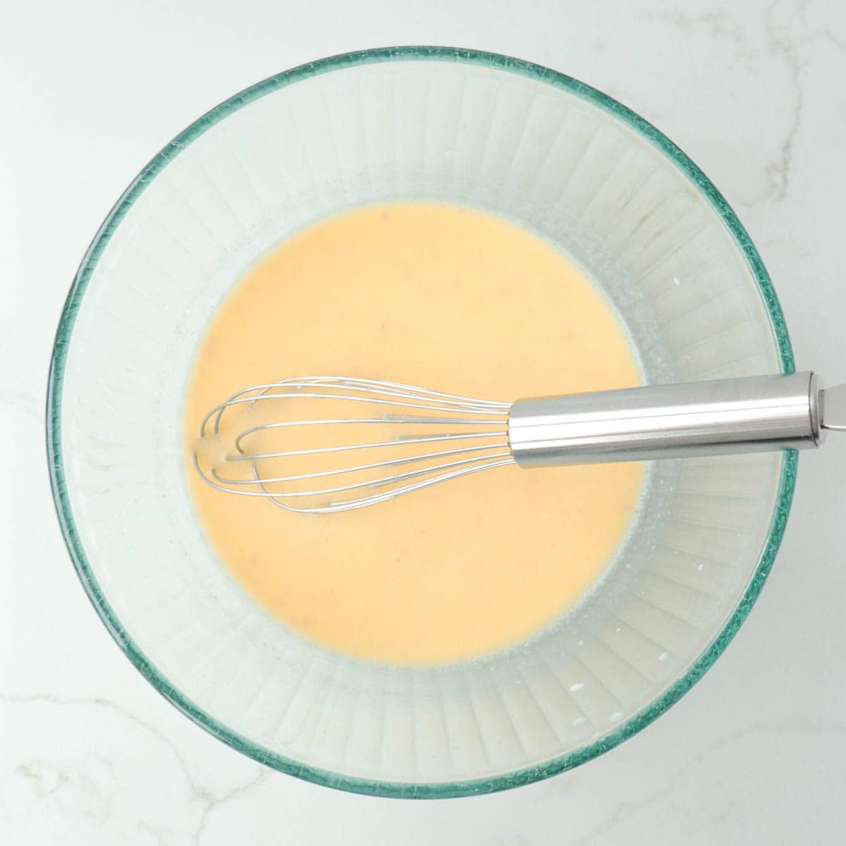 Wet ingredients whisked together in a glass mixing bowl.