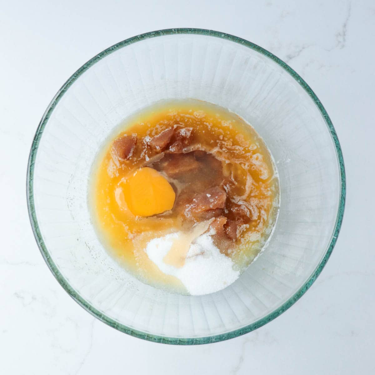 Melted butter, sugars, egg, and vanilla in a glass mixing bowl.