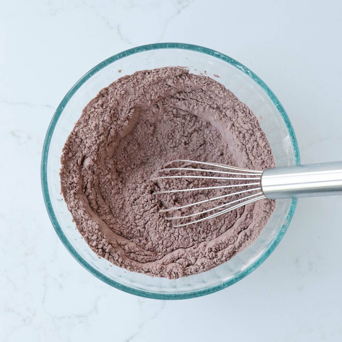 Dry ingredients combined in a glass mixing bowl.
