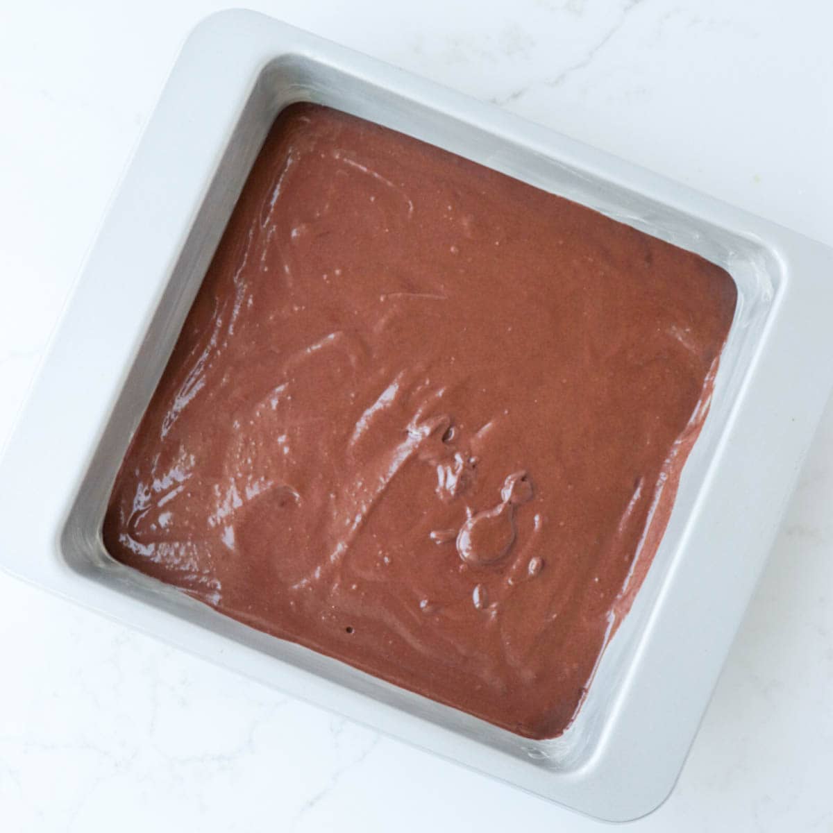 Cake batter in metal pan before baking.