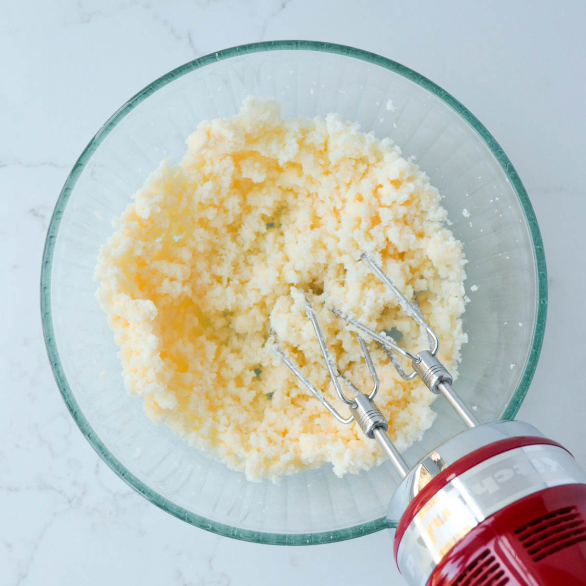 Butter and sugar creamed together in a glass mixing bowl.