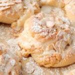 Almond bun topped with sliced almond, powdered sugar, and a drizzle of icing.